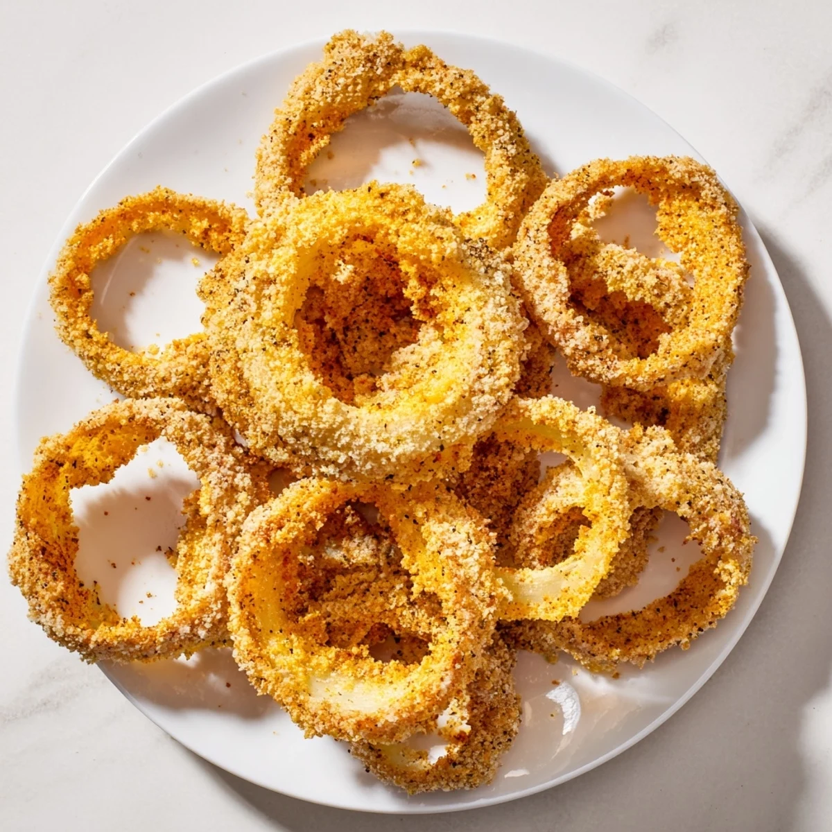 Beautifully golden and crunchy crispy baked onion rings are perfectly arranged on a baking sheet.