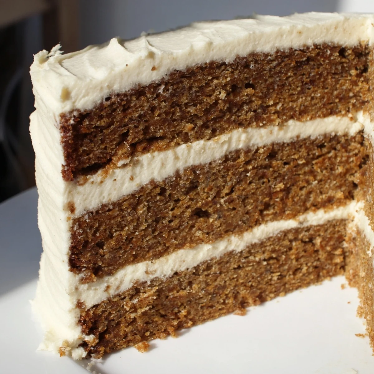 Close-up photo of the spiced gingerbread layer cake, frosted and ready to serve at a gathering.