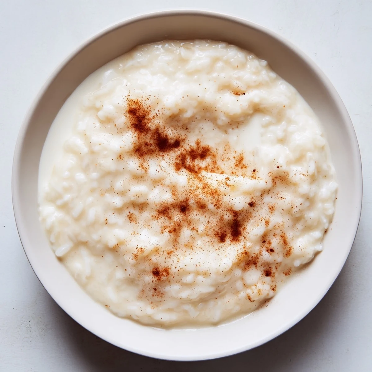 Close-up of golden brown rice pudding with cinnamon, ready to be enjoyed warm; a classic comfort food.