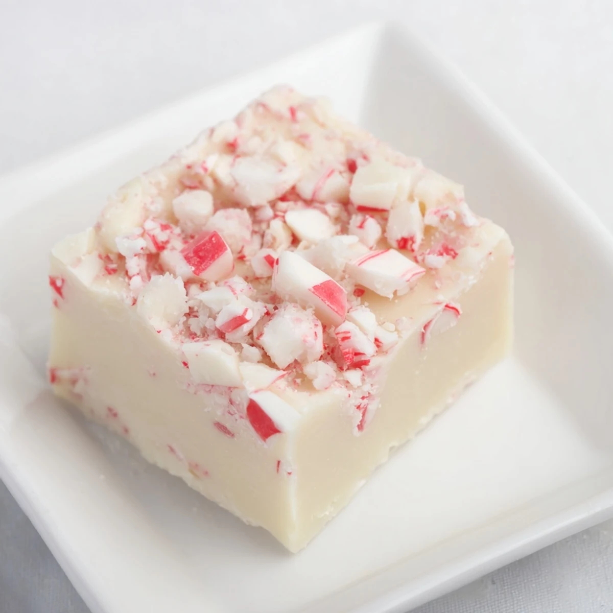 Cool, glistening Peppermint and White Chocolate Fudge sprinkled with crushed candy canes, ready to enjoy.