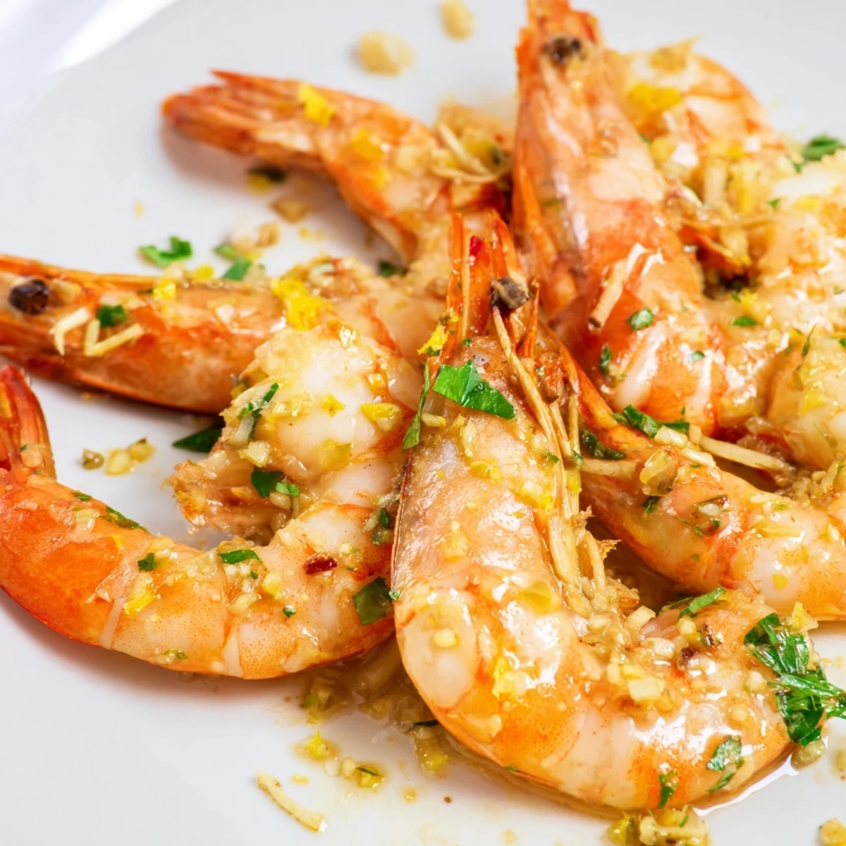 Close-up of Lemon Garlic Butter Prawns glistening in a skillet with fresh parsley and lemon wedges.