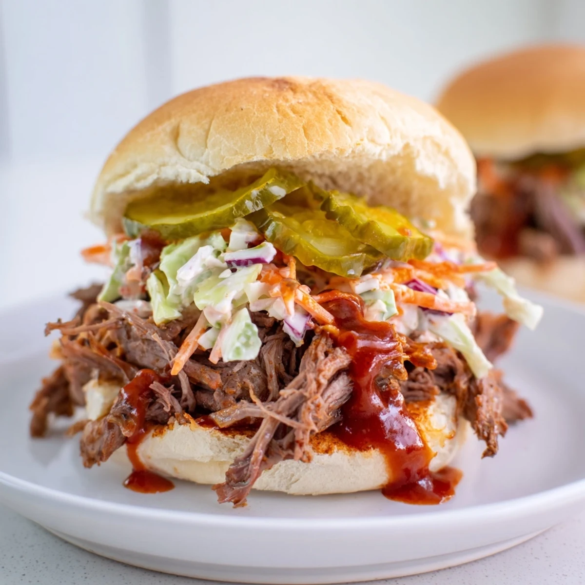 Slow-cooked shredded beef brisket piled high on soft slider buns, topped with creamy coleslaw and tangy dill pickles for a savory party bite.