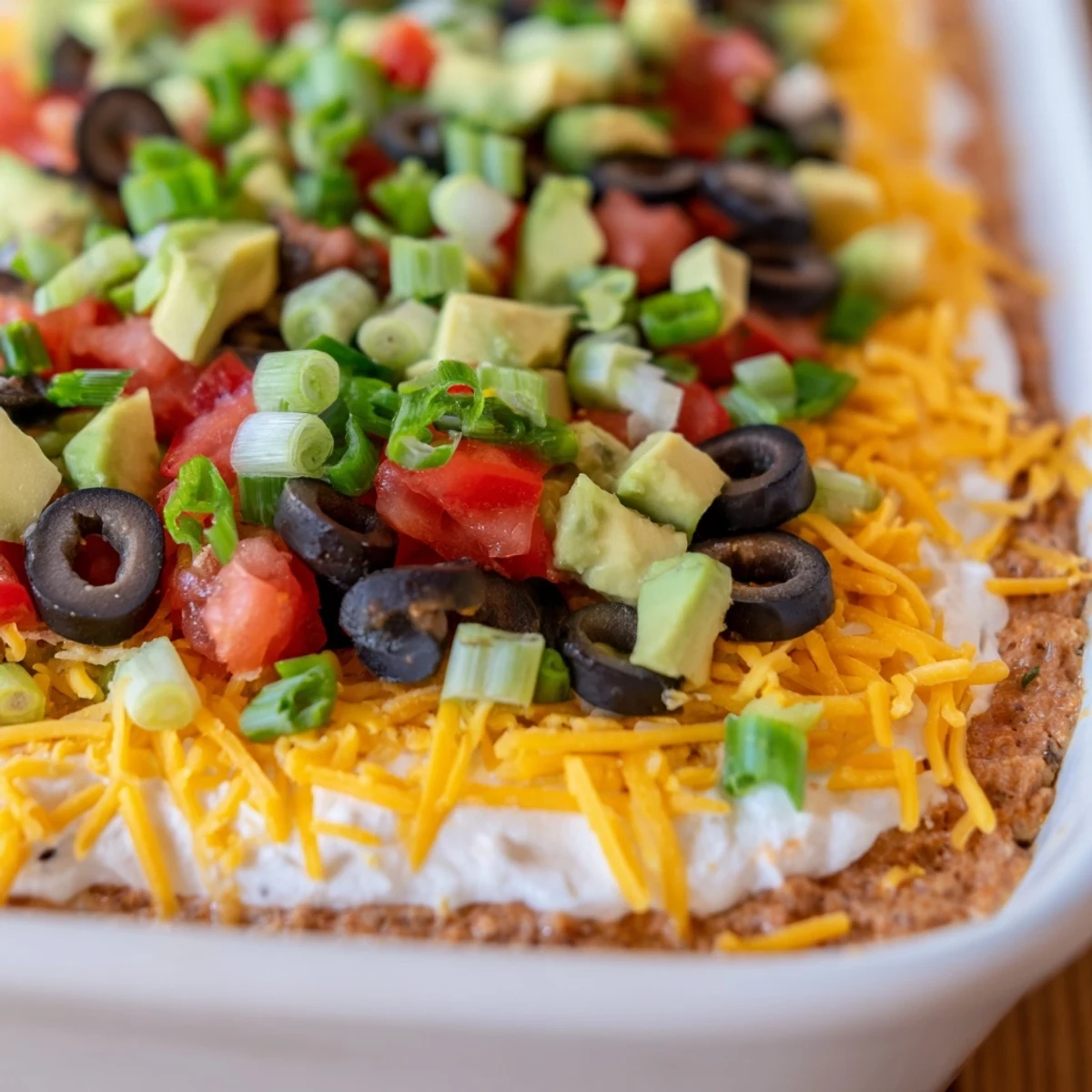 A close-up of Ultimate Layered Taco Dip reveals its zesty layers of beans, creamy cheese, and chunky salsa.