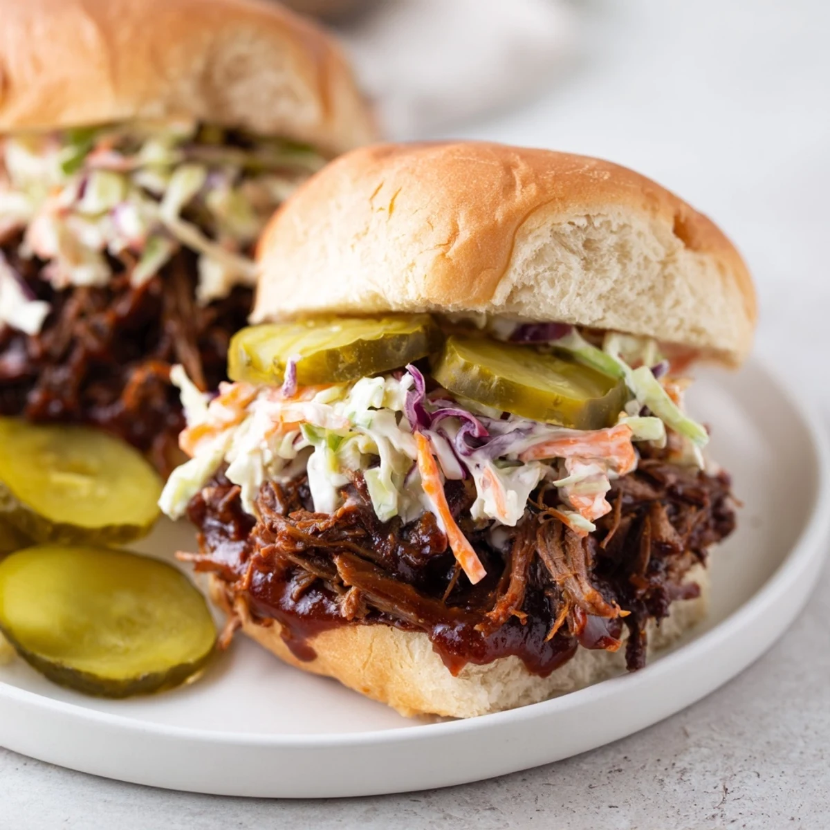 Golden beef brisket sliders with creamy coleslaw and dill pickle slices on a soft bun.