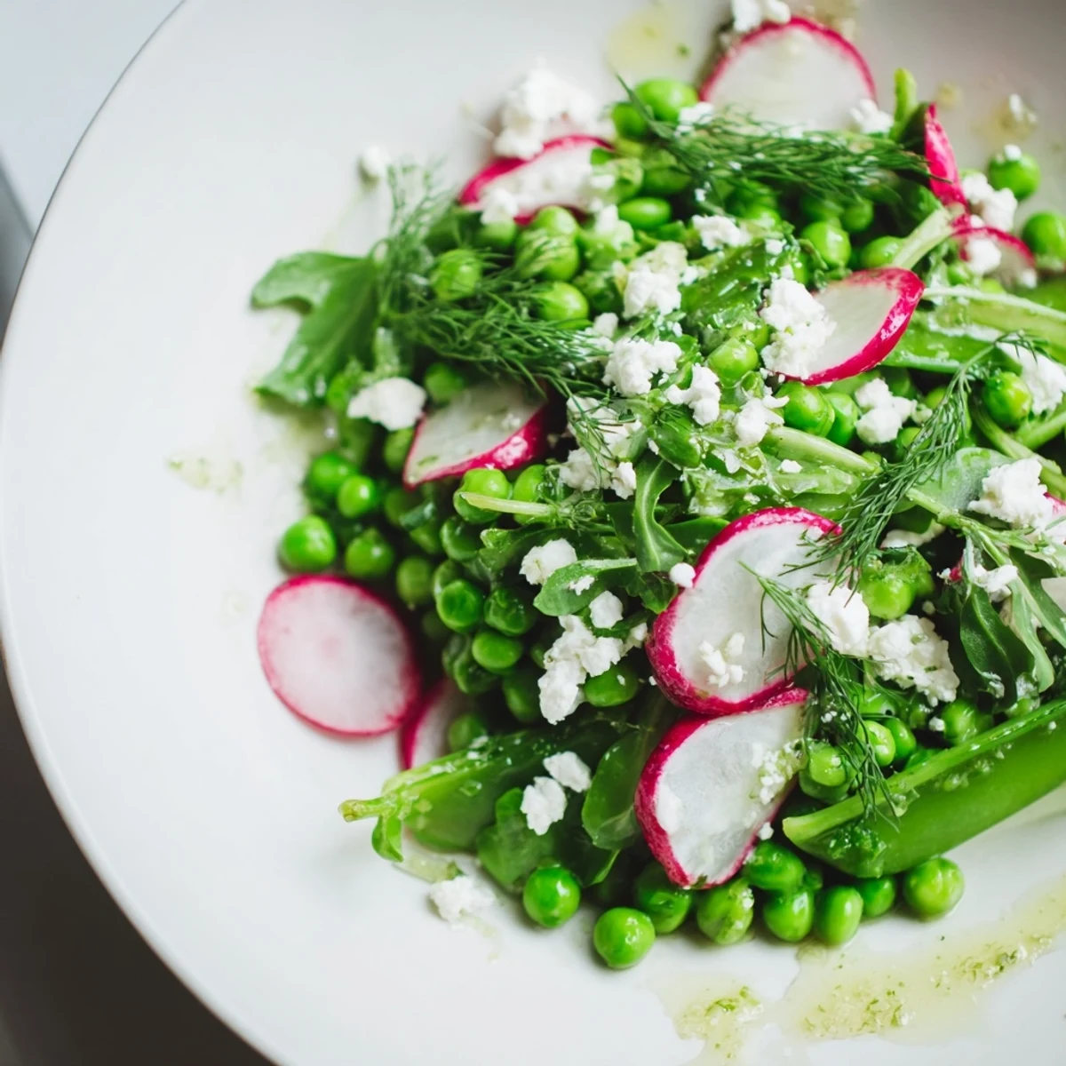 A vibrant Spring Pea Salad with Radishes and Feta, ready to serve, garnished with dill and mint for a refreshing Mediterranean side dish.