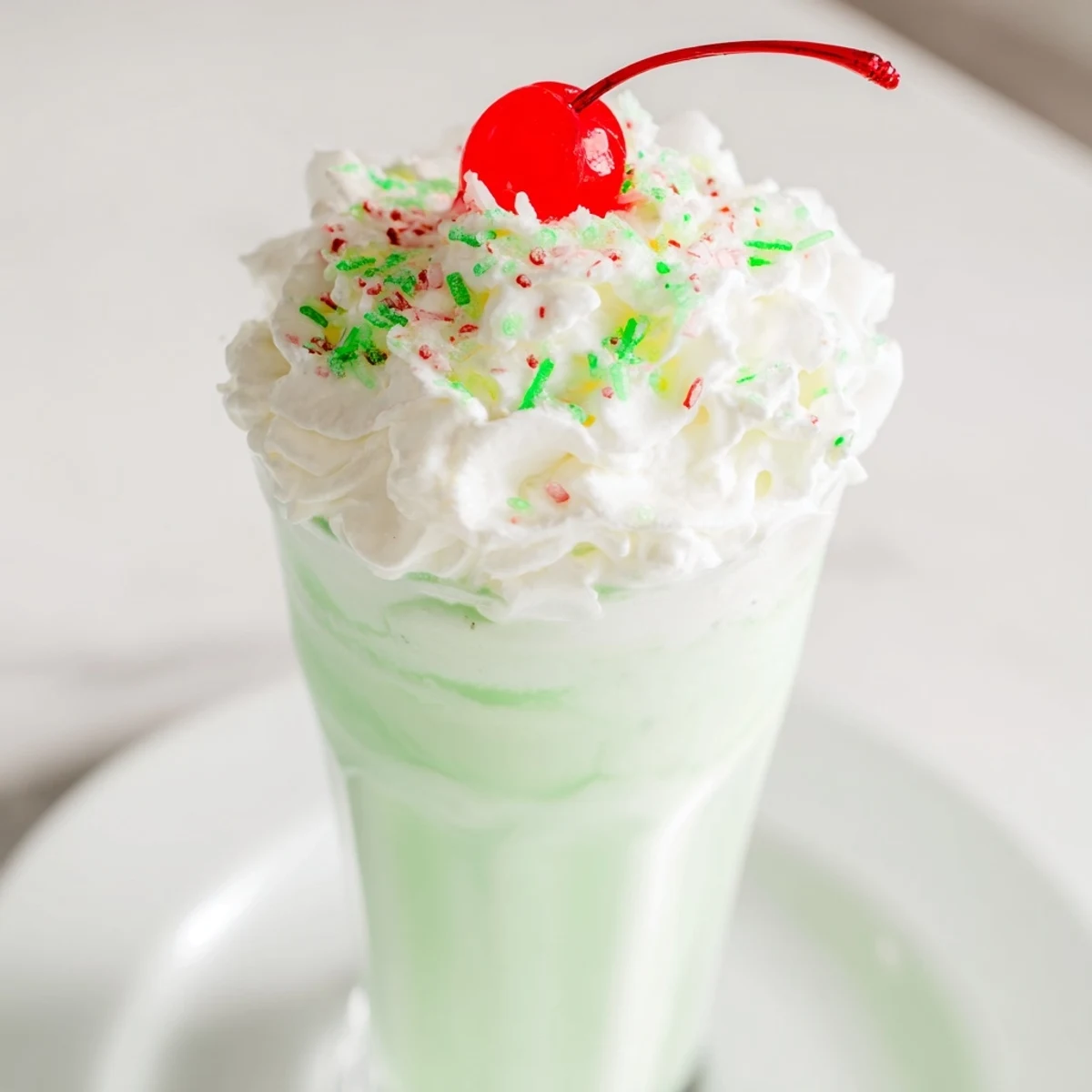 Homemade Copycat Shamrock Shake served in tall glasses with whipped cream and green sprinkles.