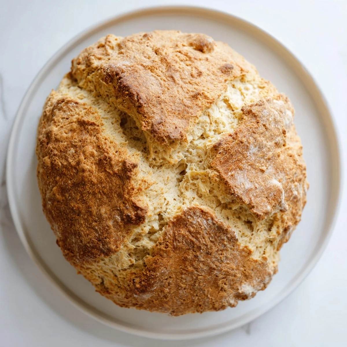 A rustic Authentic 4-Ingredient Irish Soda Bread loaf with a deep cross on top, perfect alongside hearty stew.