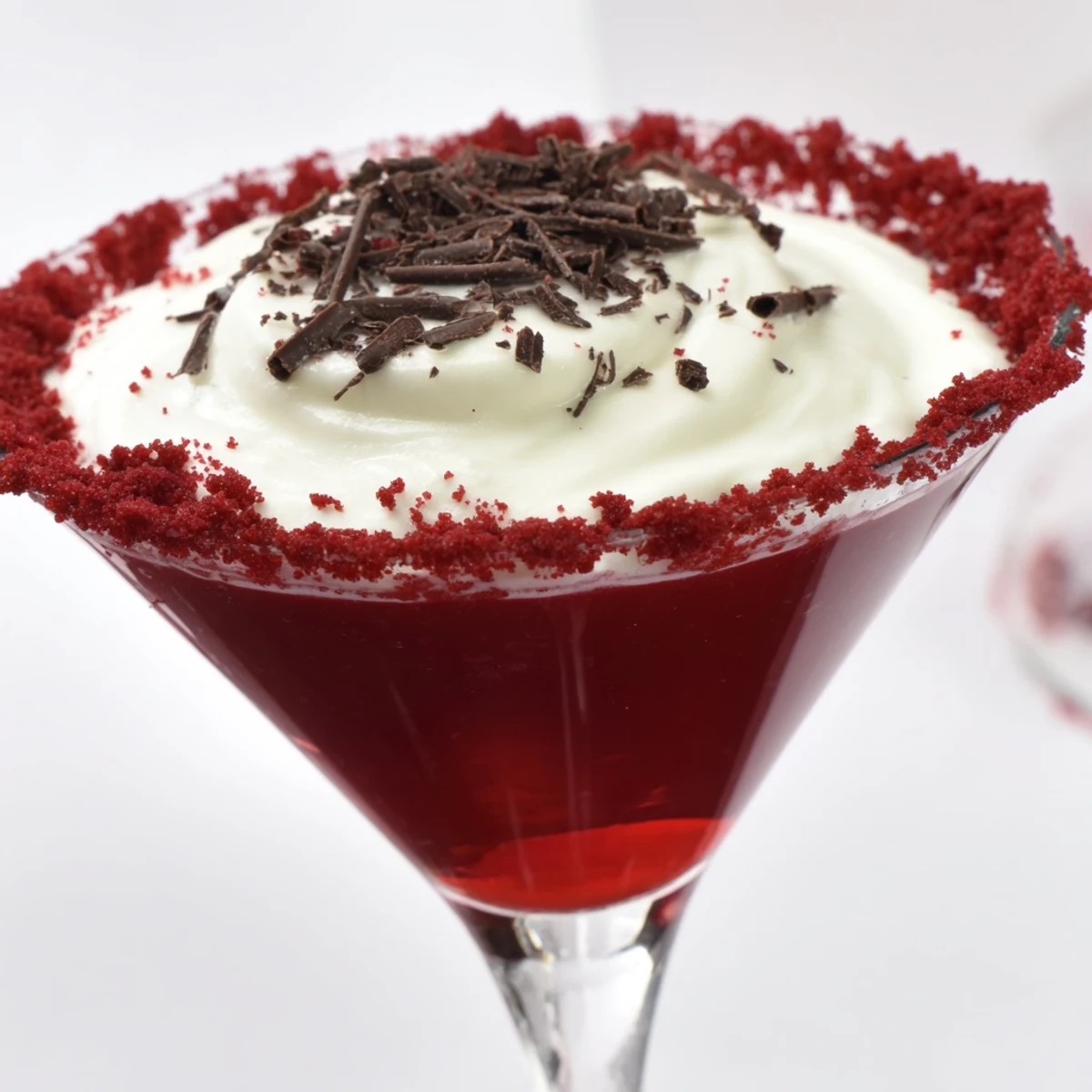 The Decadent Red Velvet Martini features a deep red hue, creamy texture, and chocolate garnish in a chilled glass.