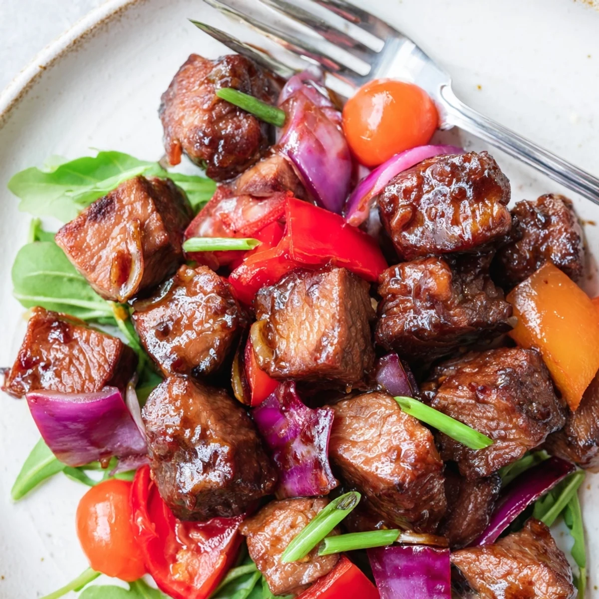 Juicy Vietnamese Shaking Beef is stir-fried until caramelized, garnished with fresh scallions and paired with steamed rice for a hearty meal.