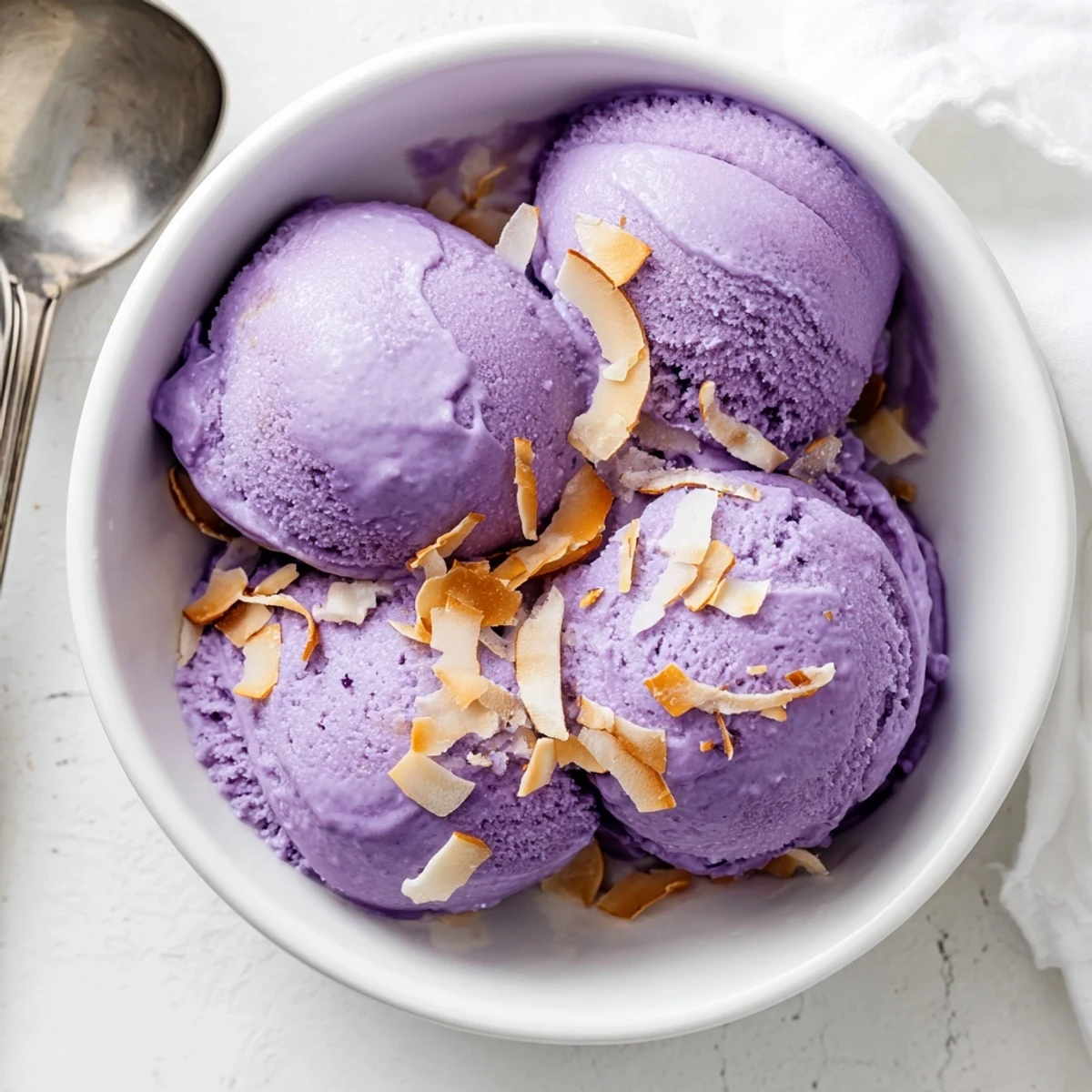 A serving of Ube Ice Cream in a waffle cone, ready to enjoy on a sunny patio table.