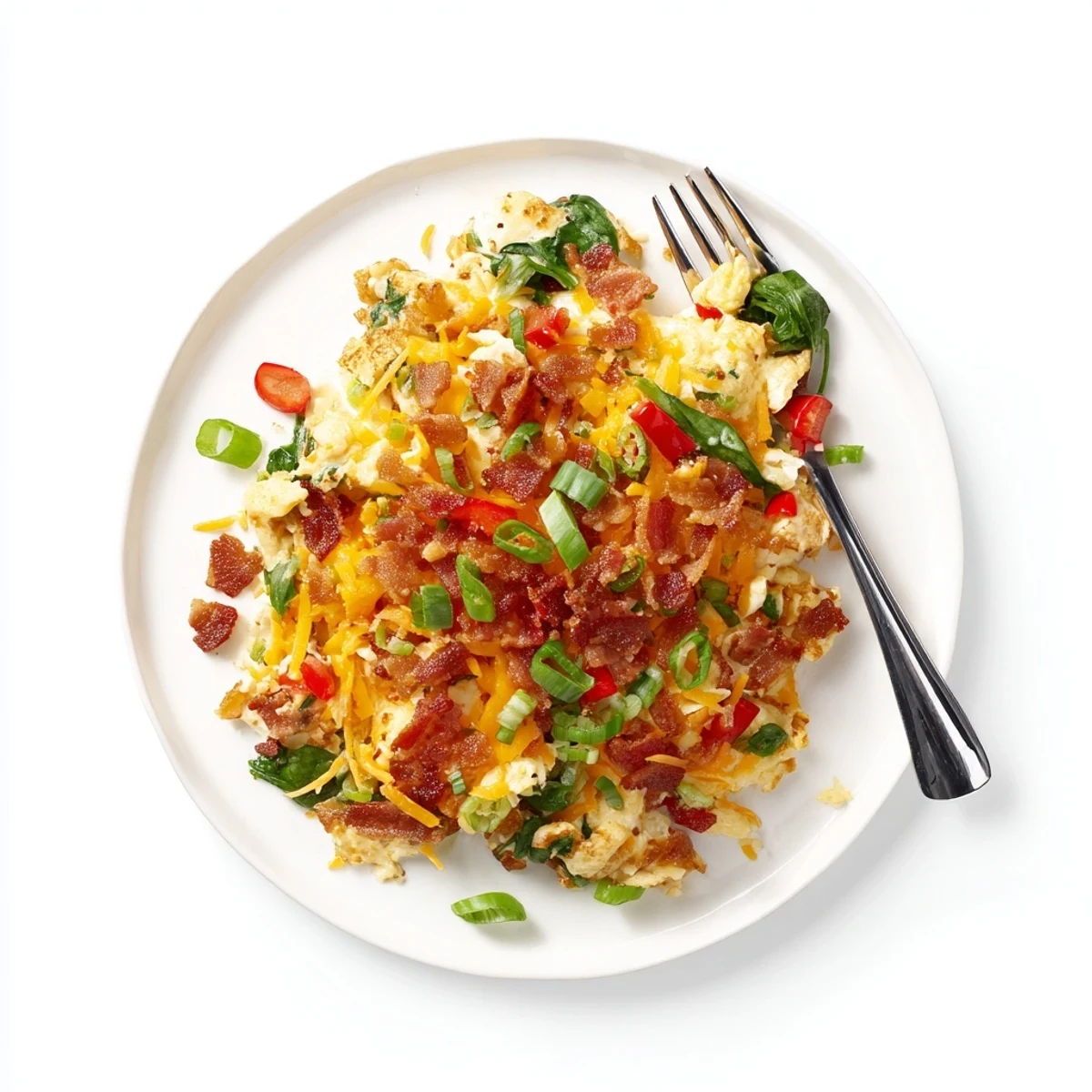 Golden Loaded Scrambled Eggs with melted cheddar, crispy bacon crumbles, and sautéed vegetables on a white plate.