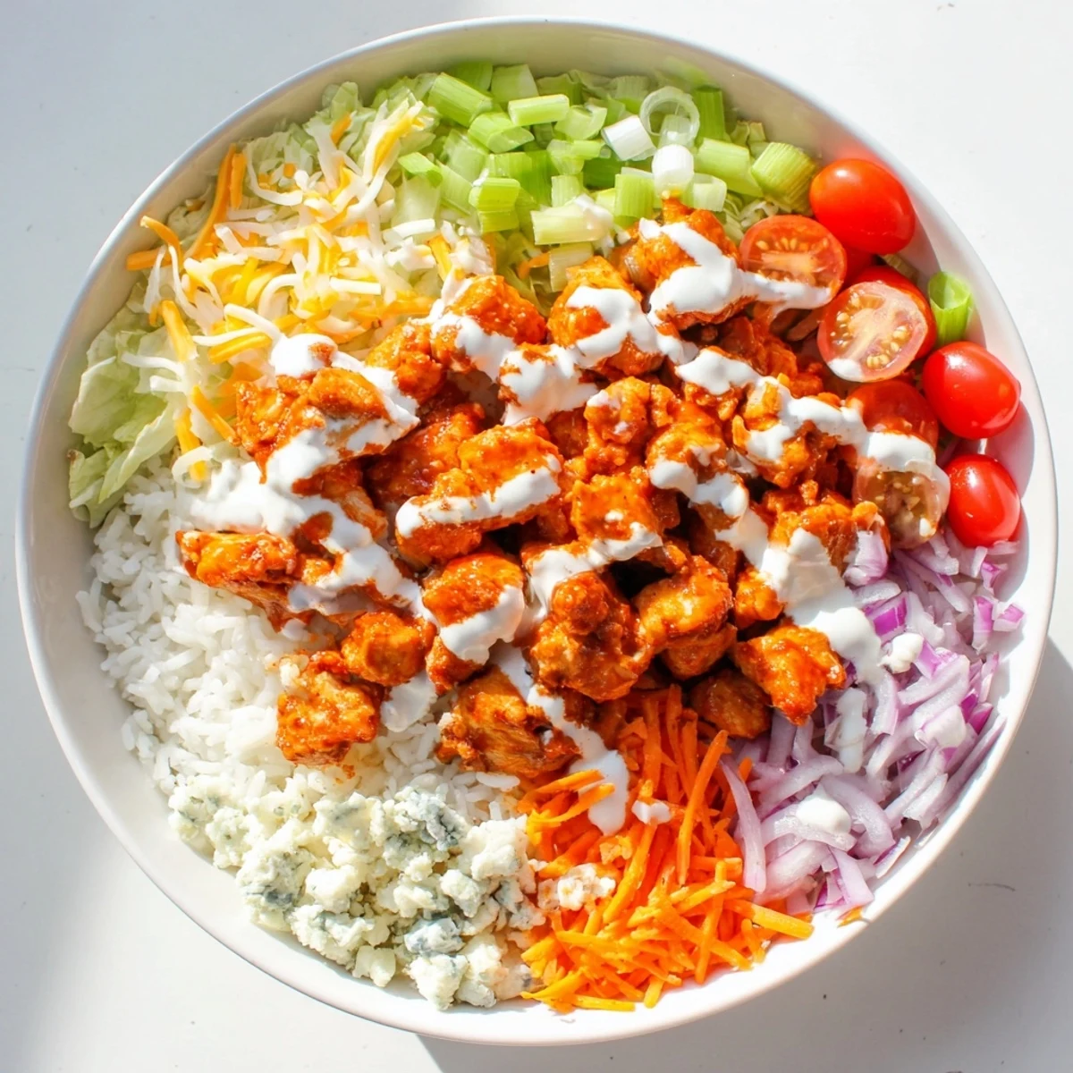 A close-up of Buffalo Chicken Bowls with melted cheddar, crisp lettuce, and tangy blue cheese crumbles in bowls.