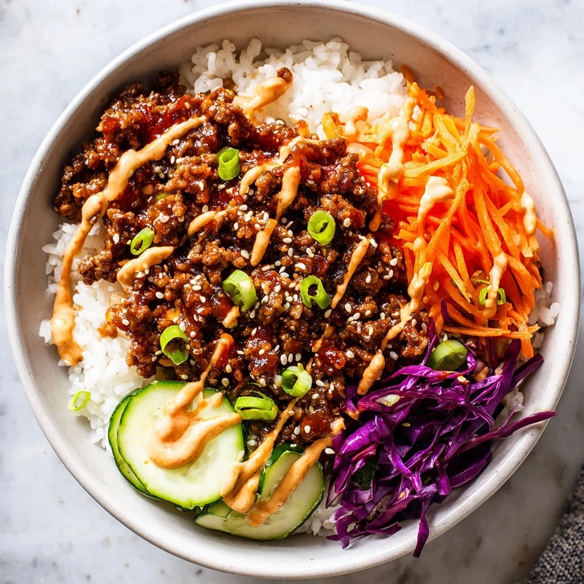 A close-up of Korean Beef Bowl with Spicy Mayo, featuring tender ground beef and crisp veggies over fluffy rice, drizzled with creamy spicy mayo.