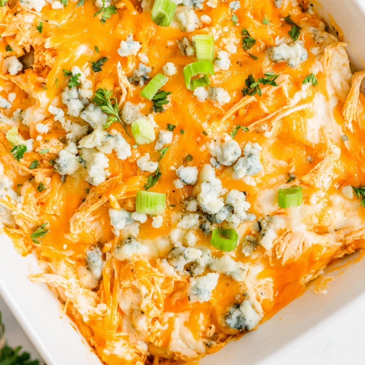 Creamy Buffalo Chicken Cheese Bake topped with green onions and blue cheese crumbles on a rustic wooden table