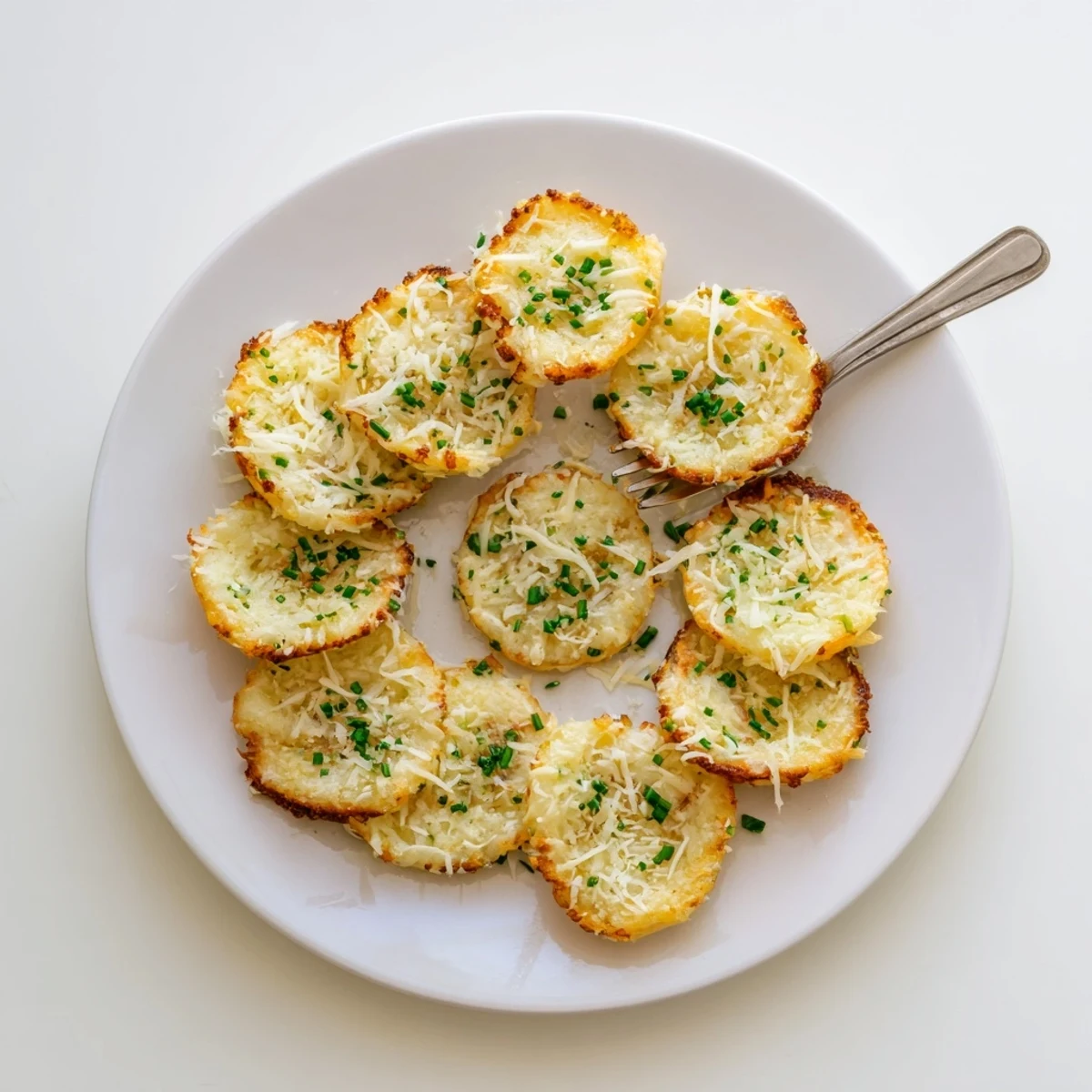 Golden cottage cheese chips arranged on a wooden board, garnished with fresh chives and ready for snacking