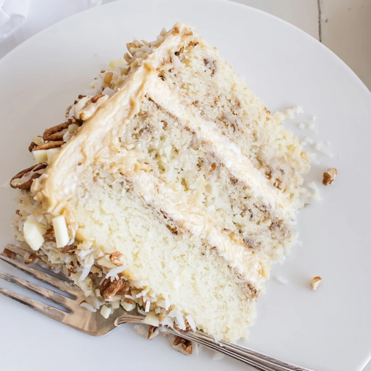 Generous slice of White German Chocolate Cake displaying moist white crumb and caramelized coconut topping