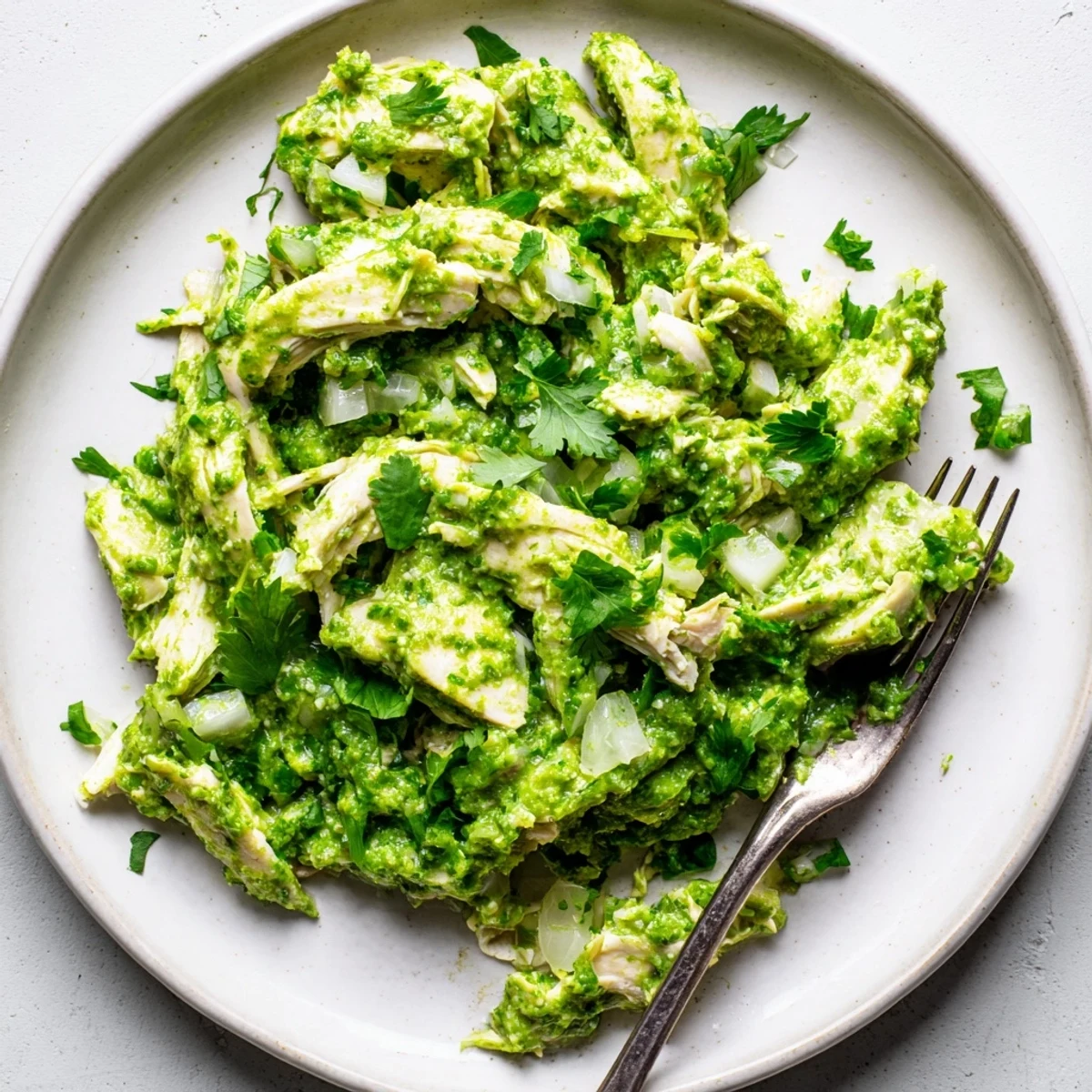 Tender chicken simmered in zesty salsa verde with diced onion and jalapeño, ready for warm corn tortillas