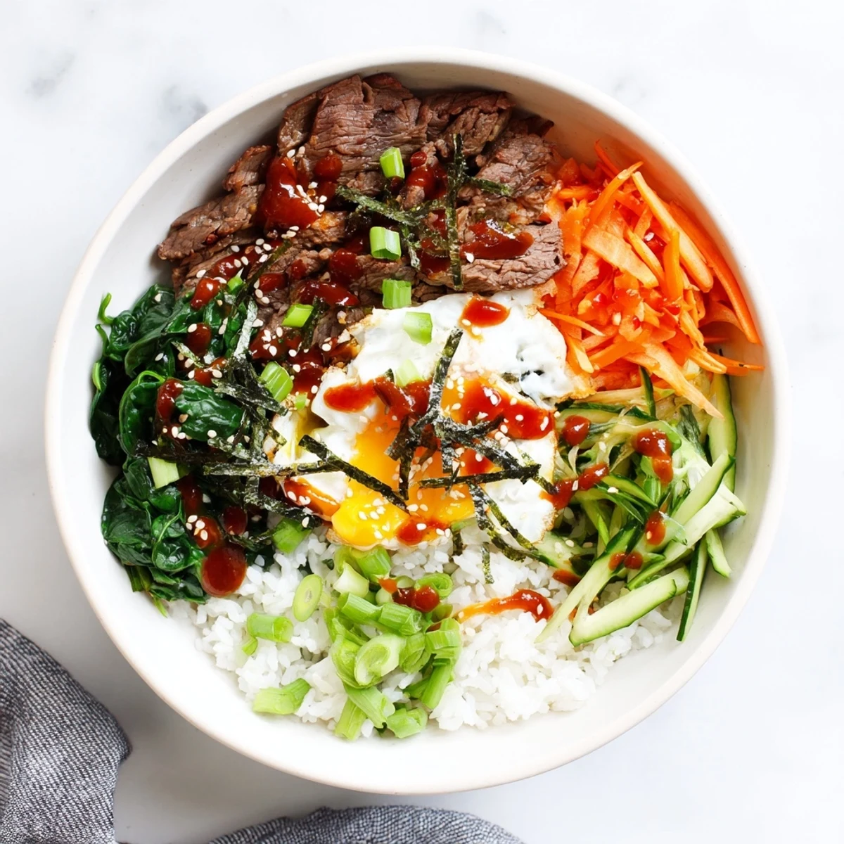 Korean-inspired breakfast bowl topped with runny fried egg and spicy gochujang drizzle