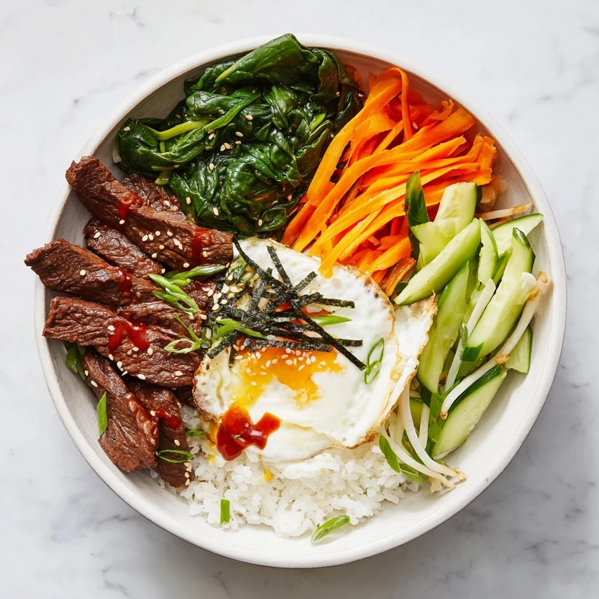 Colorful Korean breakfast bowl featuring beef over steamed rice with chili sauce