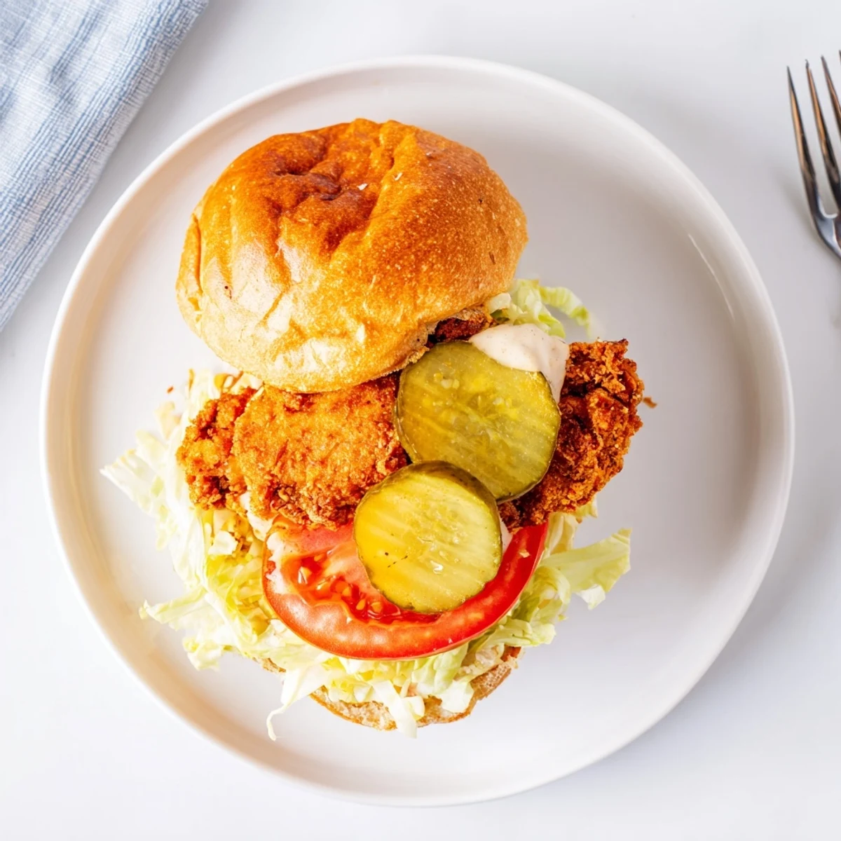 Golden brown crispy chicken fillet topped with tangy sauce and fresh vegetables between toasted brioche buns for lunch