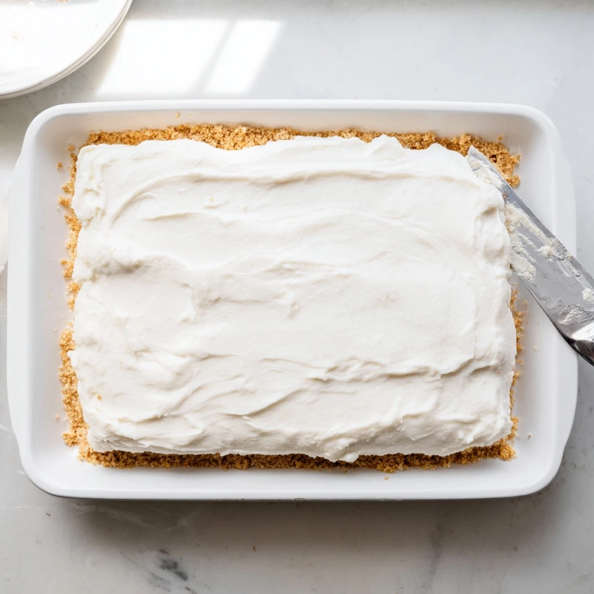 Golden vanilla church cake topped with fluffy white frosting and sprinkled with powdered sugar