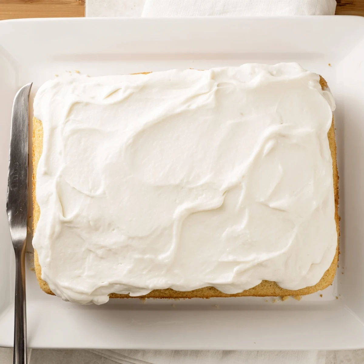 Moist church cake slice on a white plate with coffee cup nearby