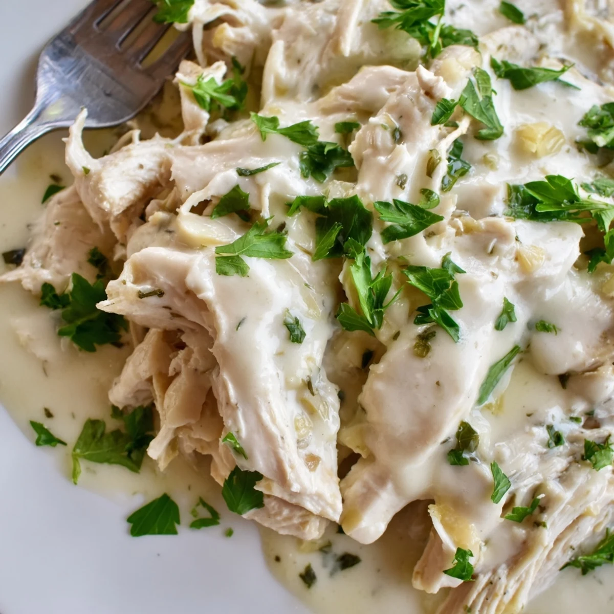 Tender slow cooker chicken coated in velvety garlic Parmesan cream sauce served over mashed potatoes