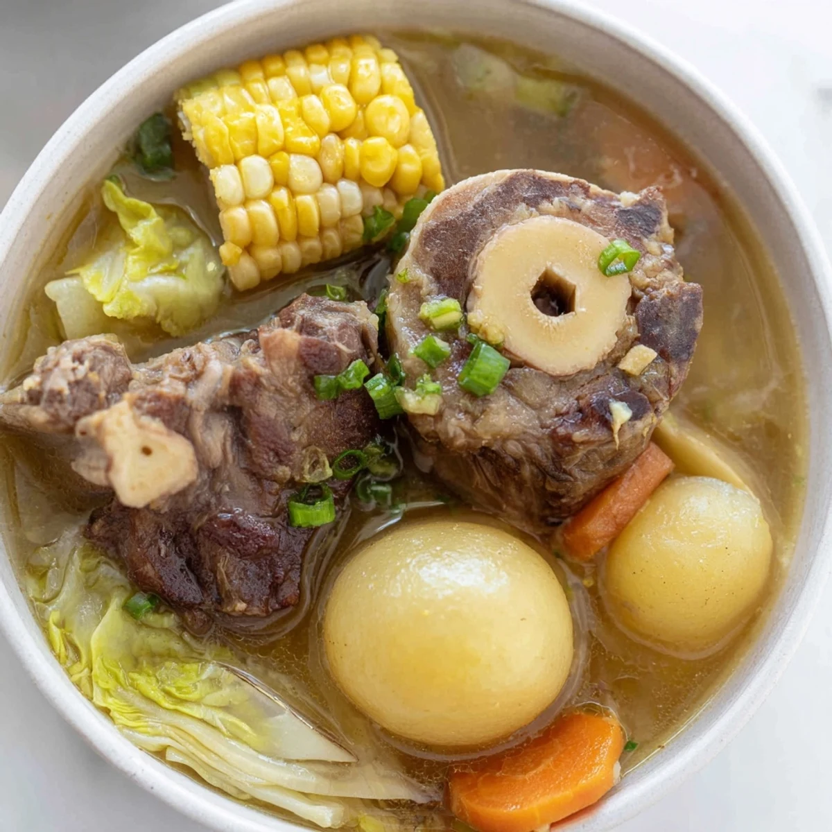 Steaming bowl of Filipino Bulalo with tender beef shank and vegetables in golden broth