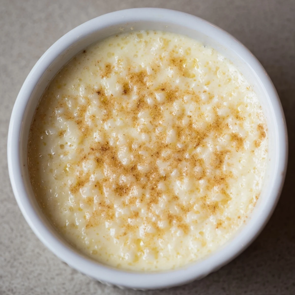 Creamy Portuguese rice custard topped with golden cinnamon sugar in white ramekins
