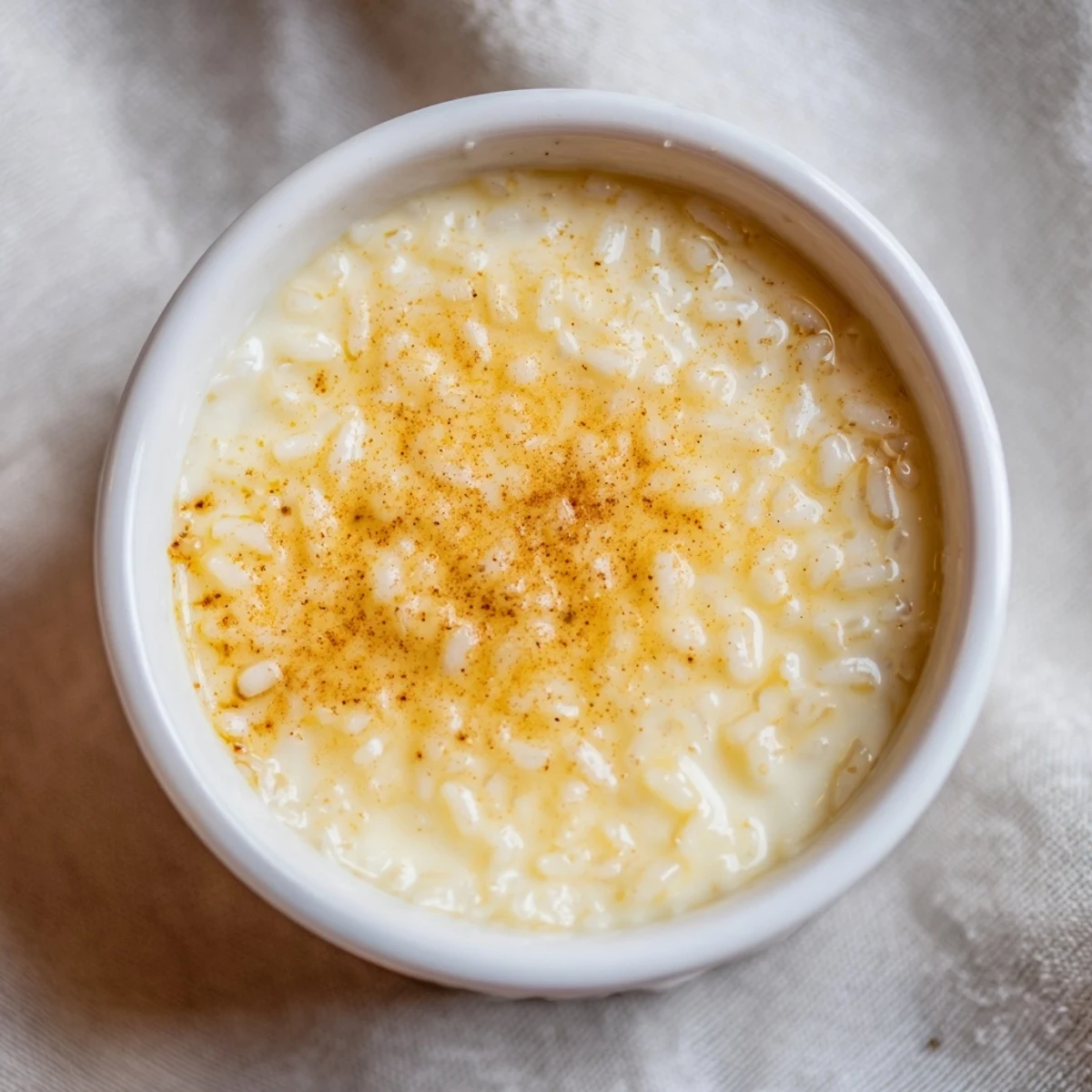 Silky Portuguese rice custard with speckled cinnamon dusting served in individual dishes