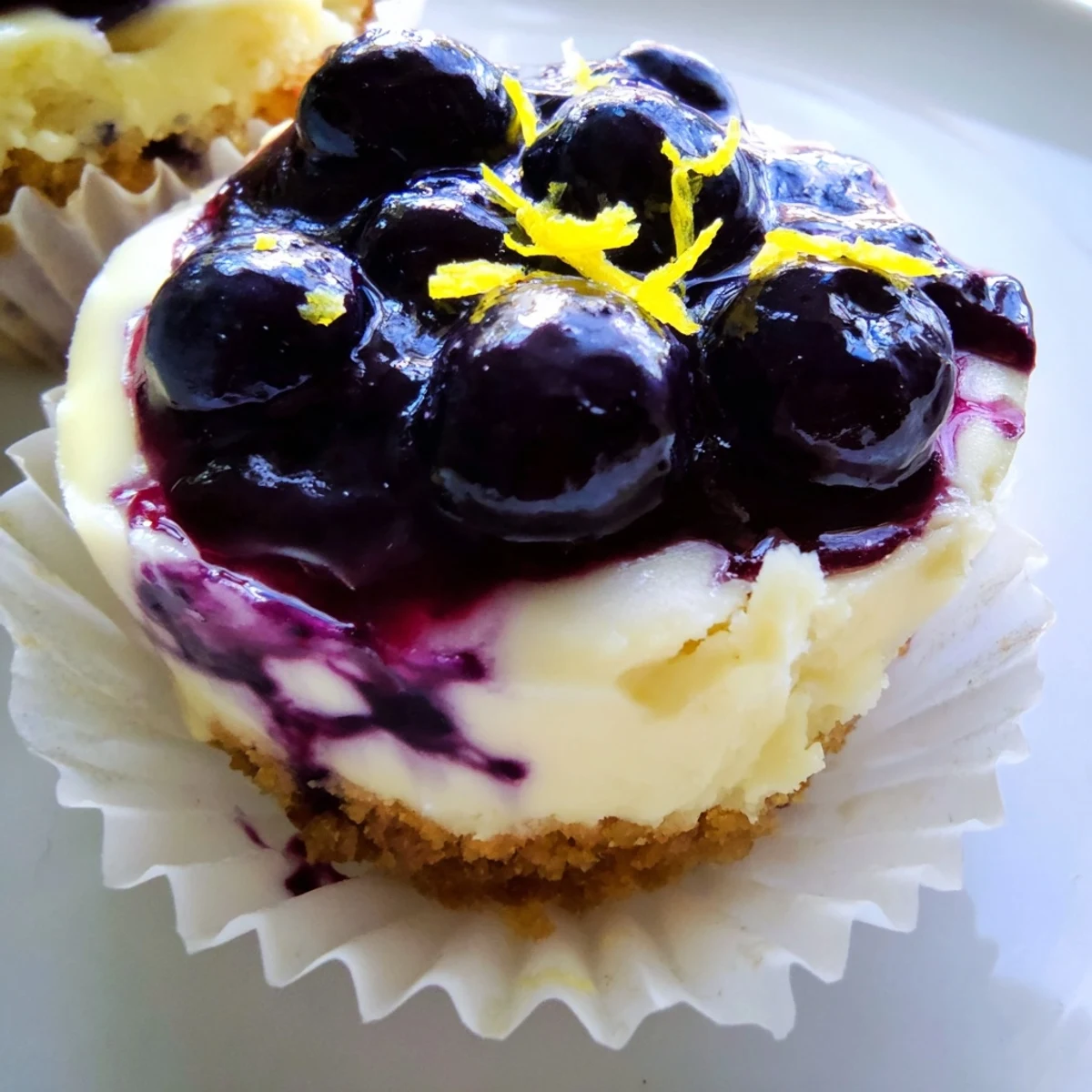 Creamy Mini Lemon Blueberry Cheesecakes swirled with homemade fruit sauce and fresh zest