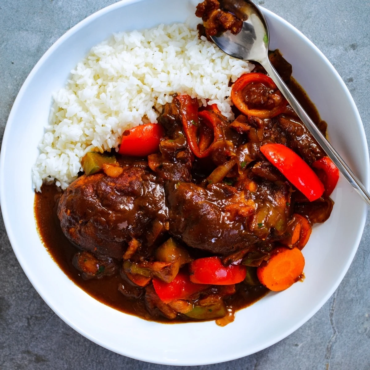 Golden-brown Jamaican brown stew chicken simmered in a rich spiced gravy with sliced bell peppers