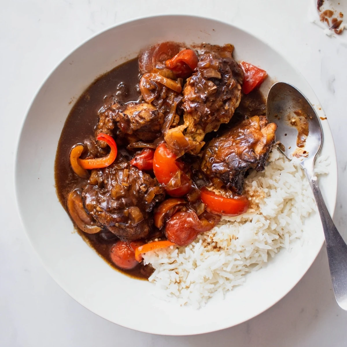 Browned chicken pieces nestled in a savory Jamaican brown stew chicken with carrots and tender vegetables