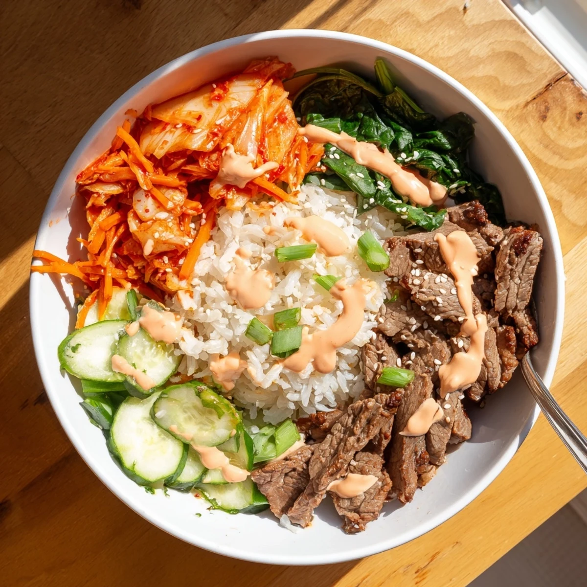 A generous scoop of spicy cream sauce tops Korean BBQ steak rice bowls with sesame seeds