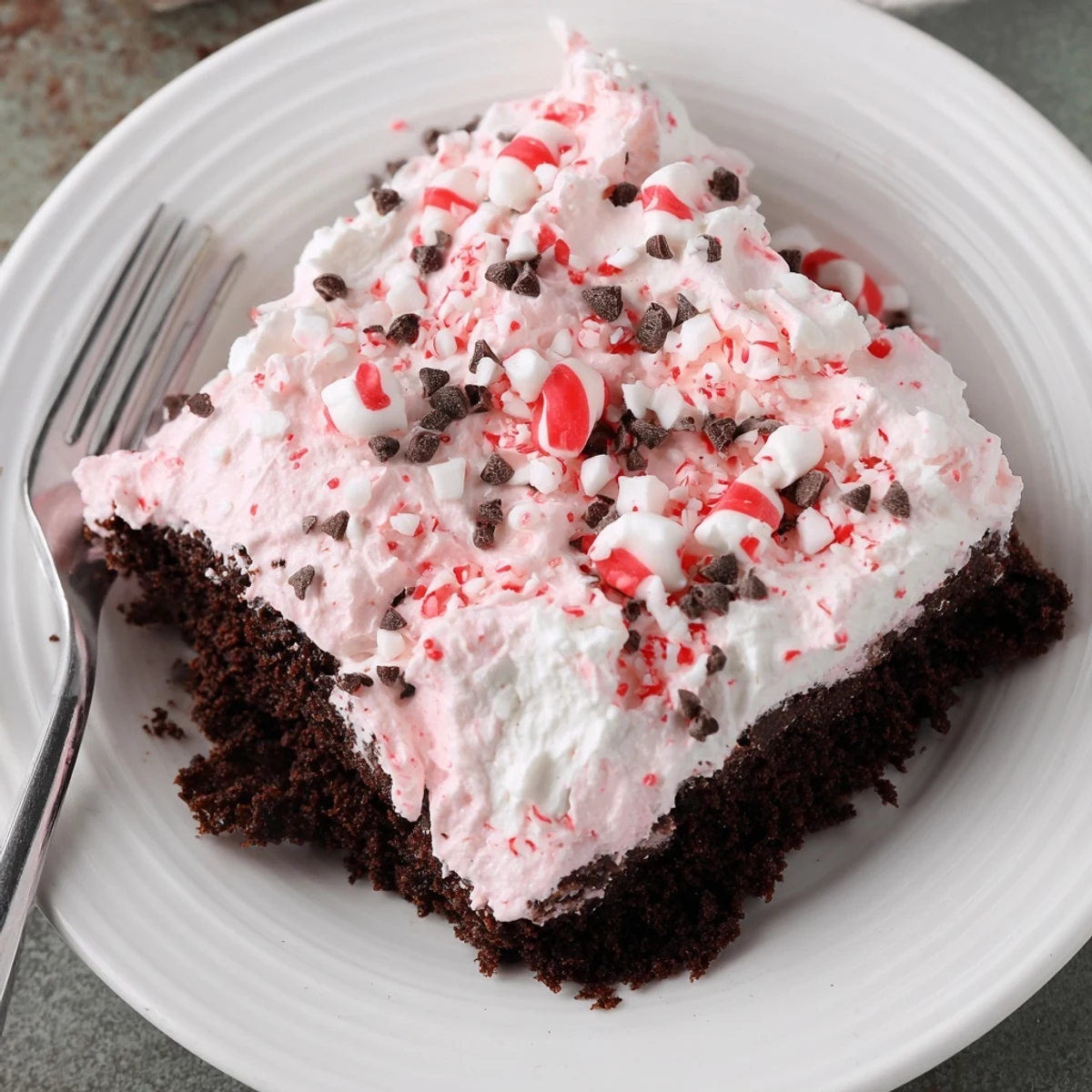 Peppermint Poke Cake chilled with fluffy whipped topping and crushed peppermint candies
