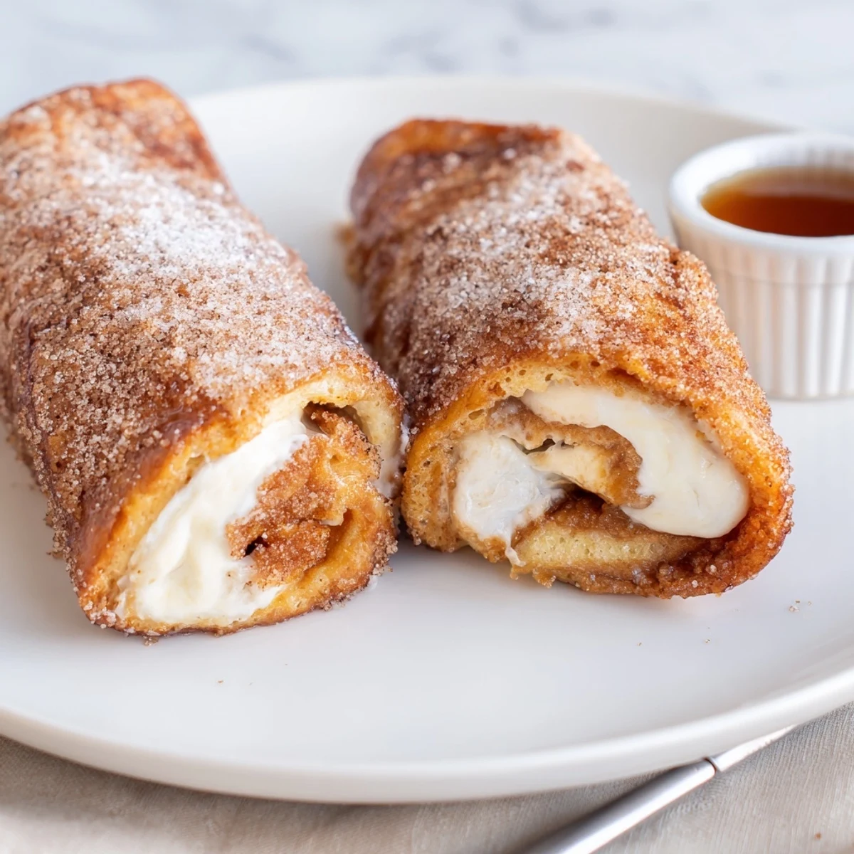 Stacked Cinnamon Roll French Toast Roll Ups on plate, creamy filling oozing