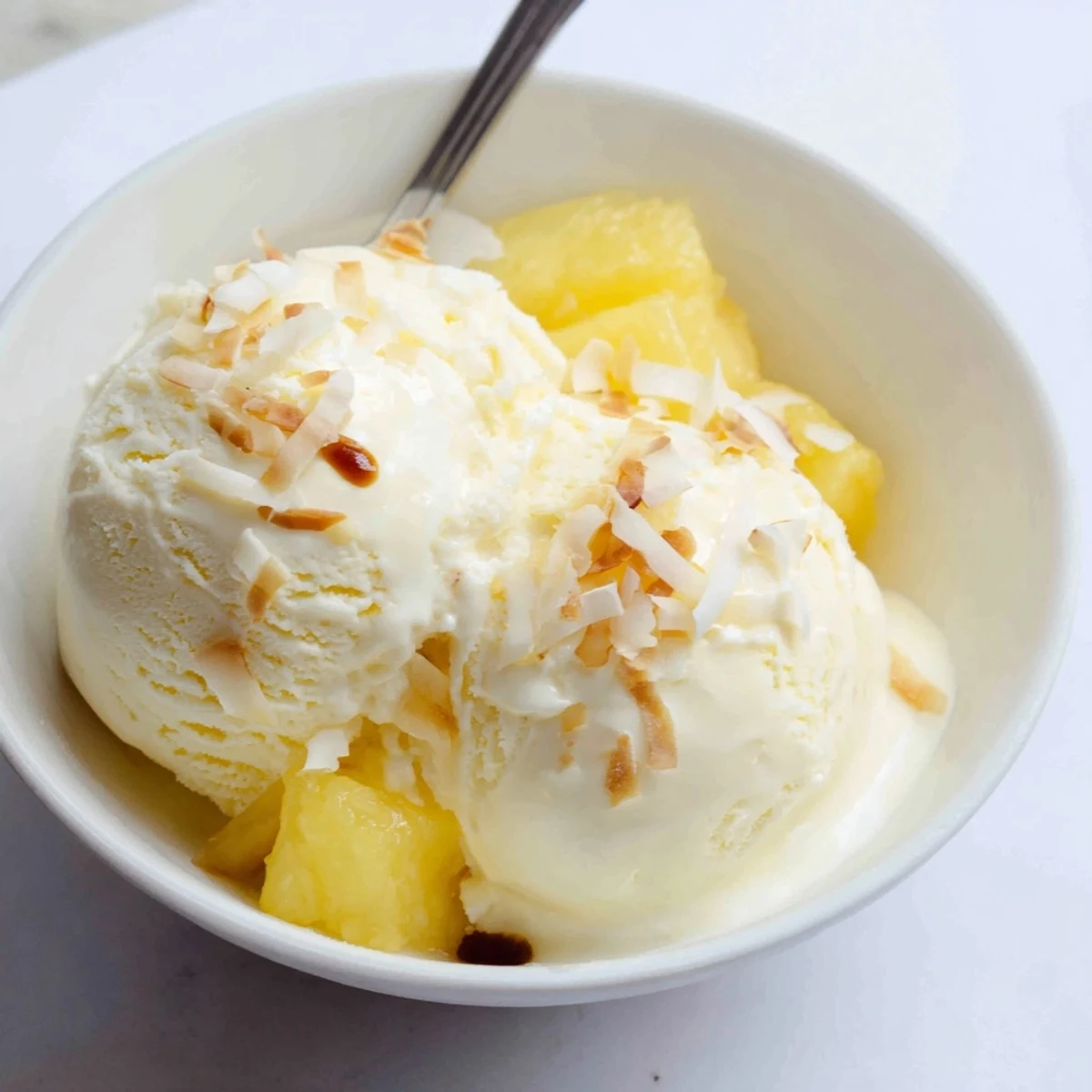 Scoops of Creamy Pineapple Ice Cream with toasted coconut and rum drizzle  