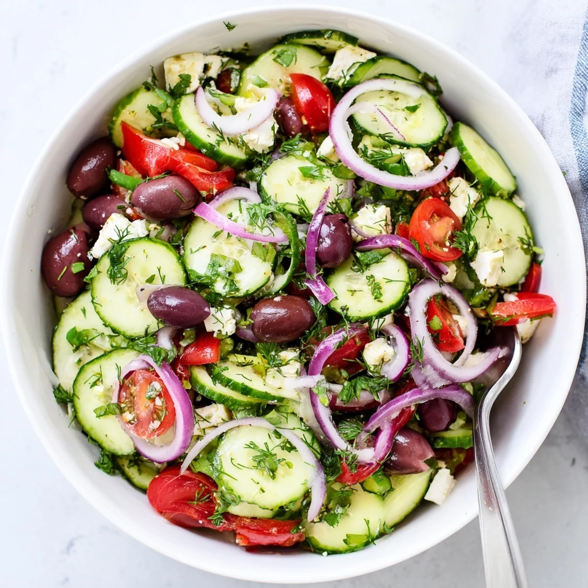 Vibrant Mediterranean cucumber salad layered with red onion, bell peppers, and Kalamata olives topped with creamy feta cheese