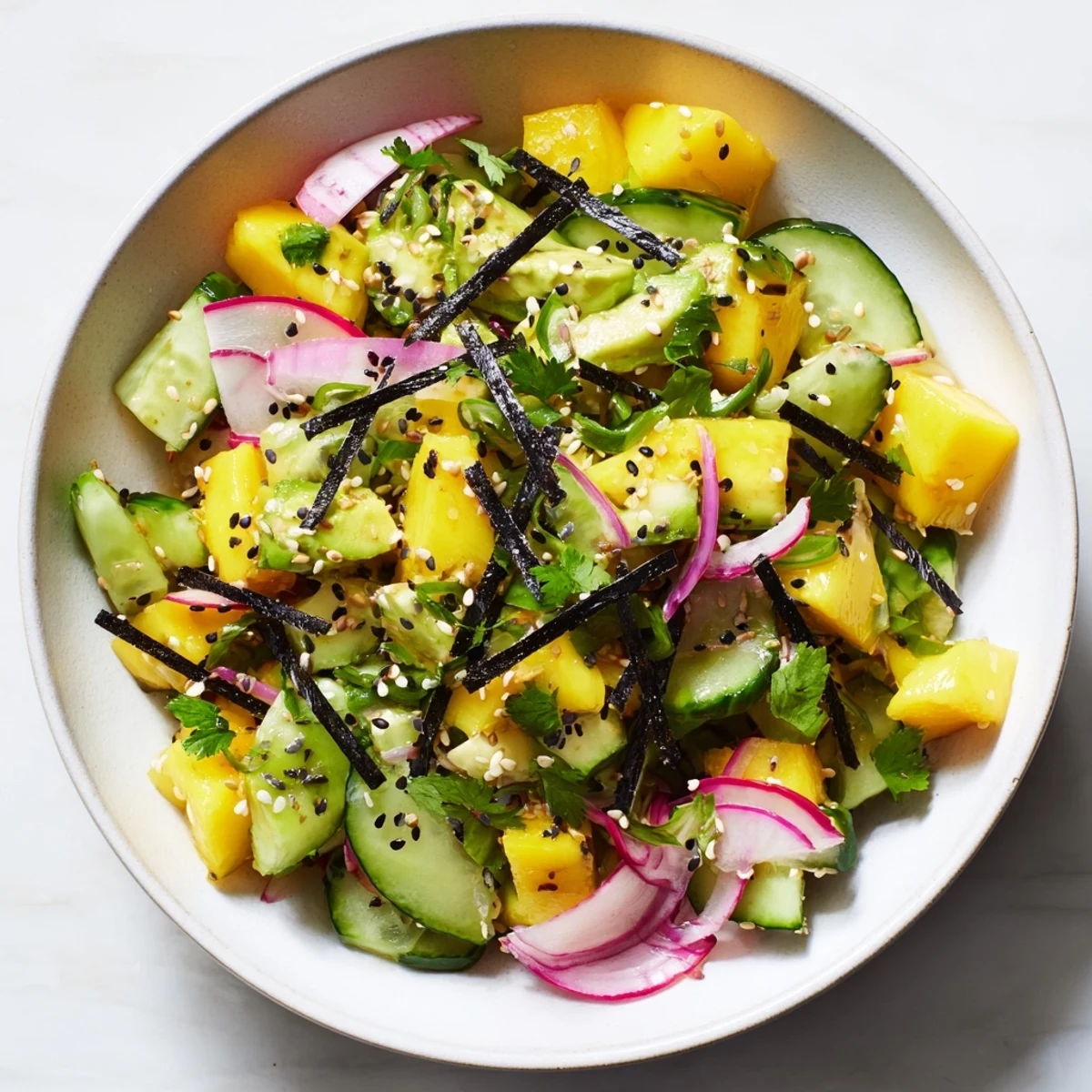 Colorful avocado mango poke salad with diced fresh vegetables and sesame seed garnish in serving bowl