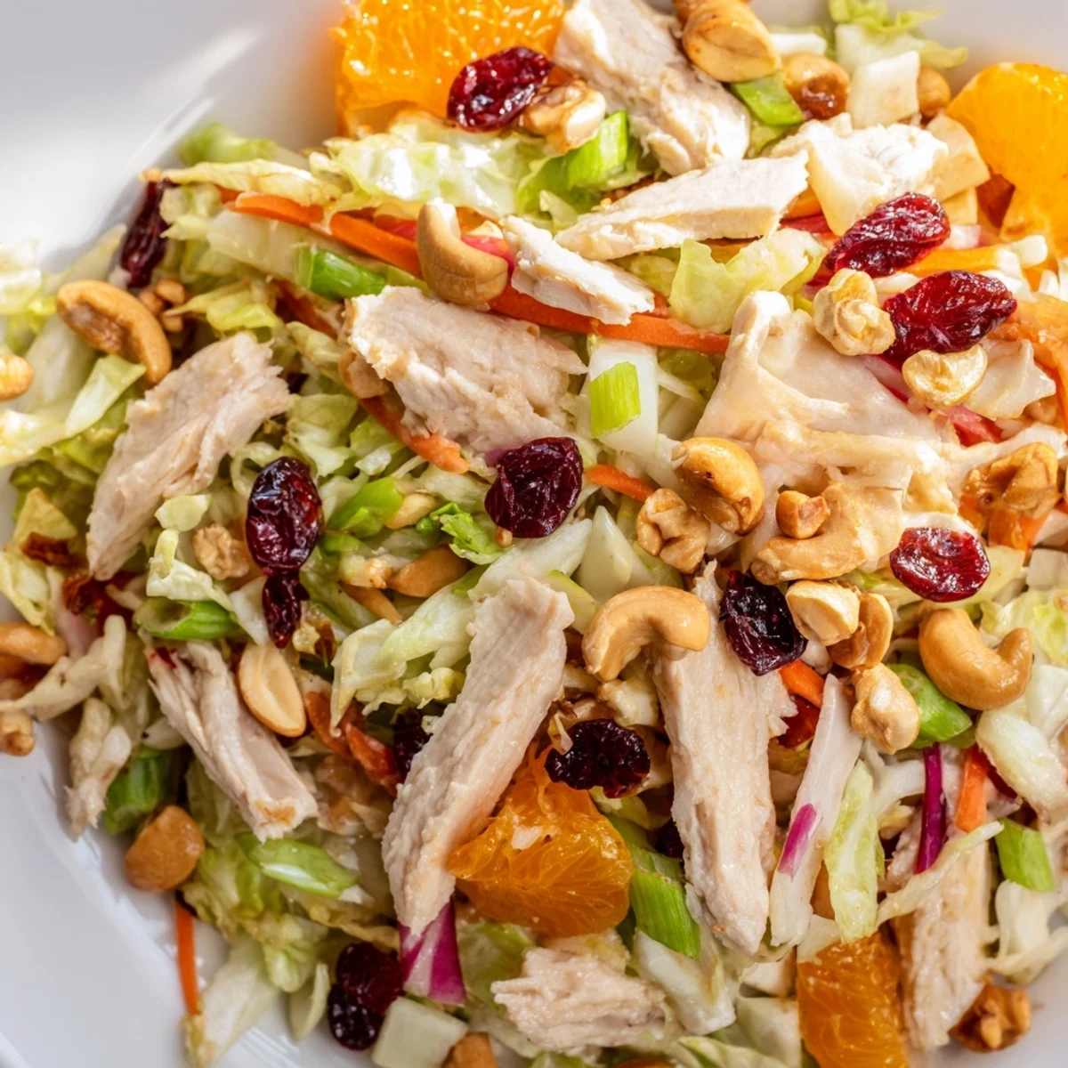 Fresh Asian chicken cranberry salad plated with roasted cashews and tangy sesame dressing