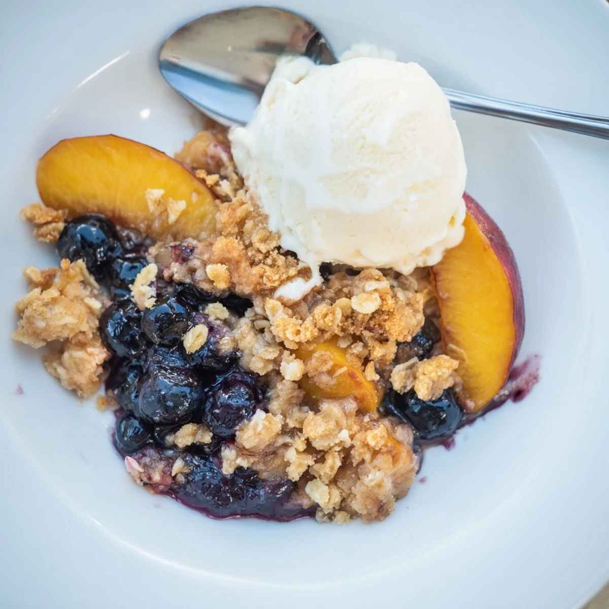 Blueberry Peach Crumble bubbling in a golden baking dish, steam rising.