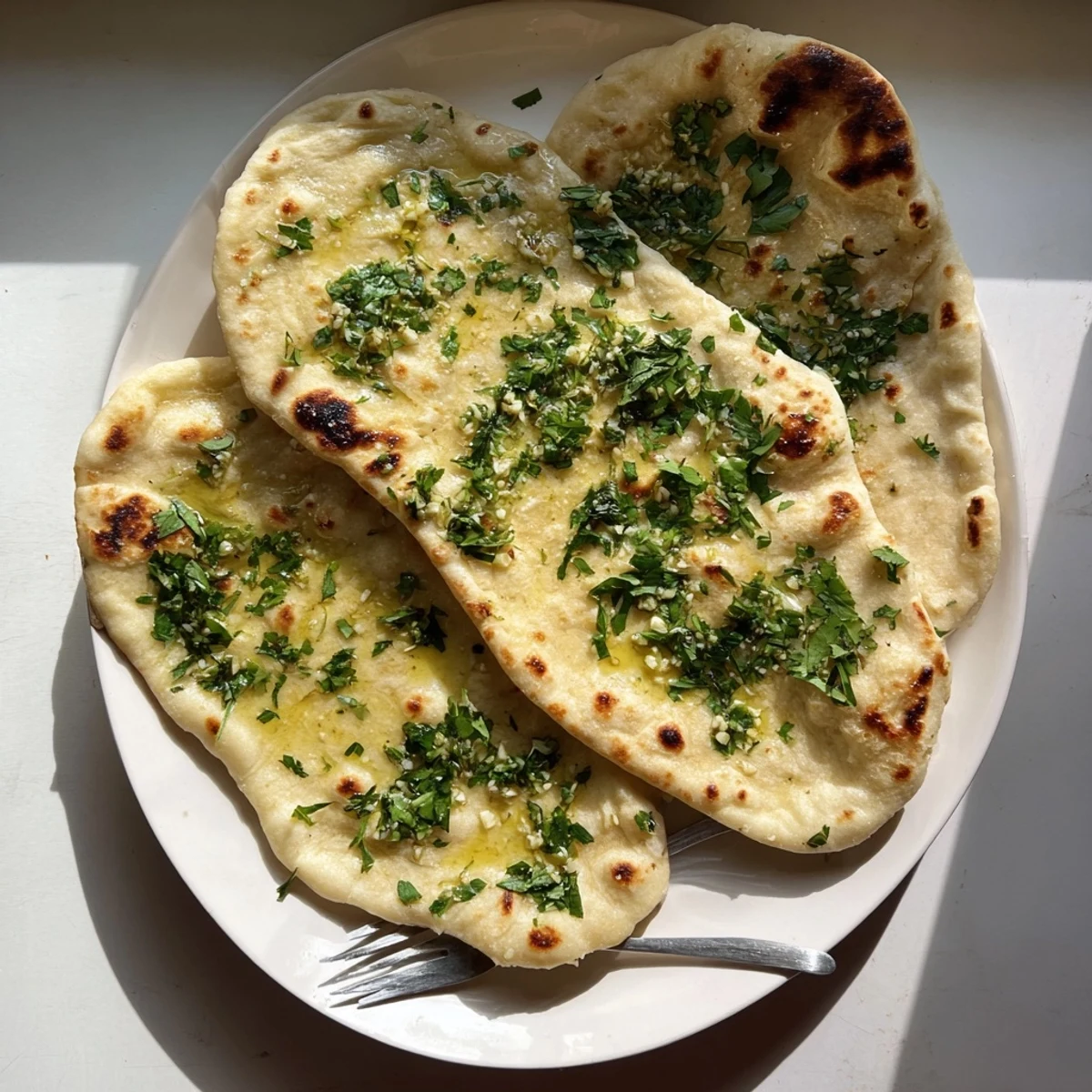 Golden brown sourdough discard soft naan brushed with melted butter and fresh herbs