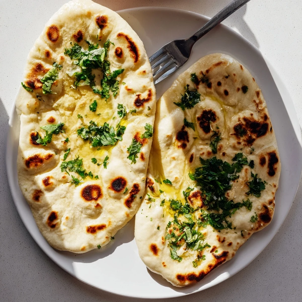 Pillowy Indian-inspired sourdough discard naan with charred bubbles from the cast iron skillet