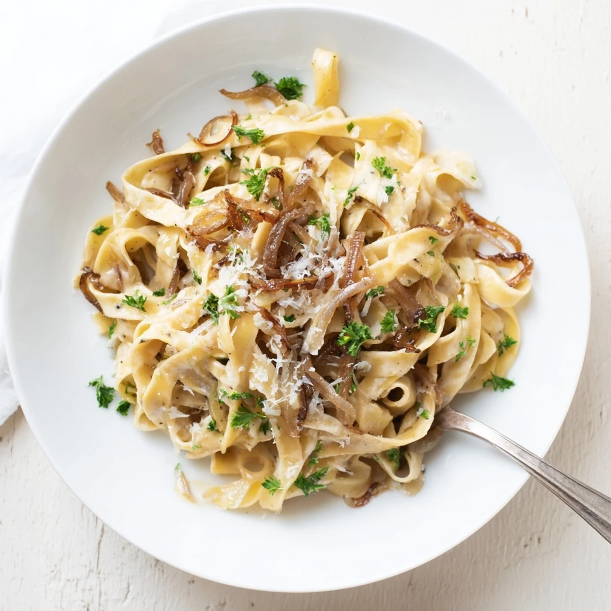 Golden brown caramelized onions coated in creamy parmesan sauce twirled around fettuccine noodles