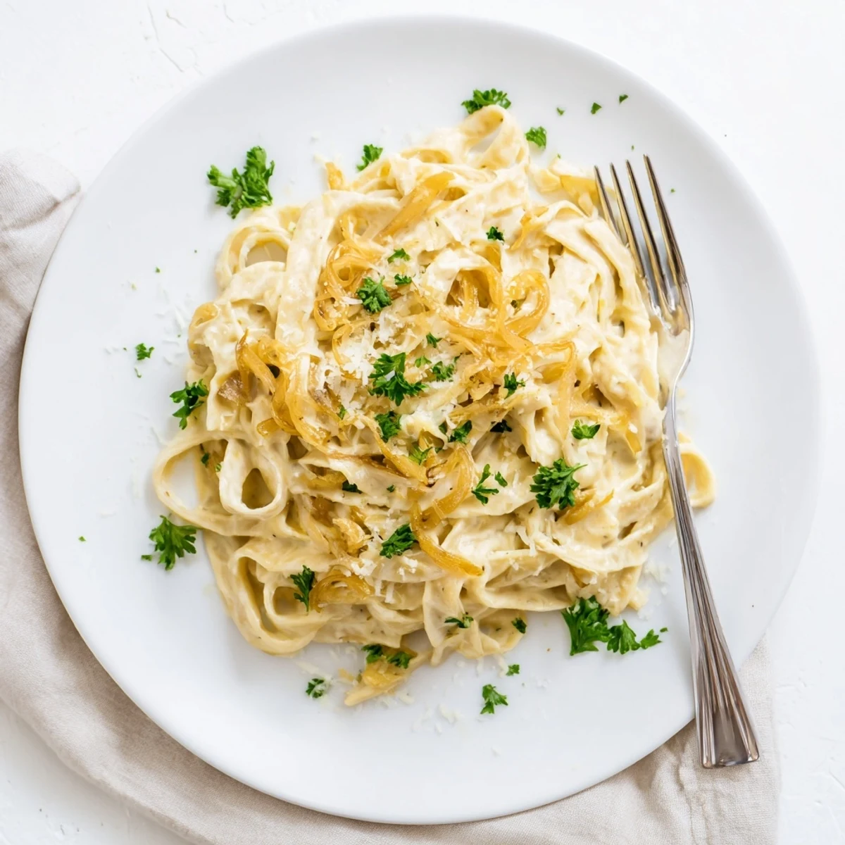 Velvety cream sauce envelopes caramelized onion pasta garnished with grated parmesan cheese