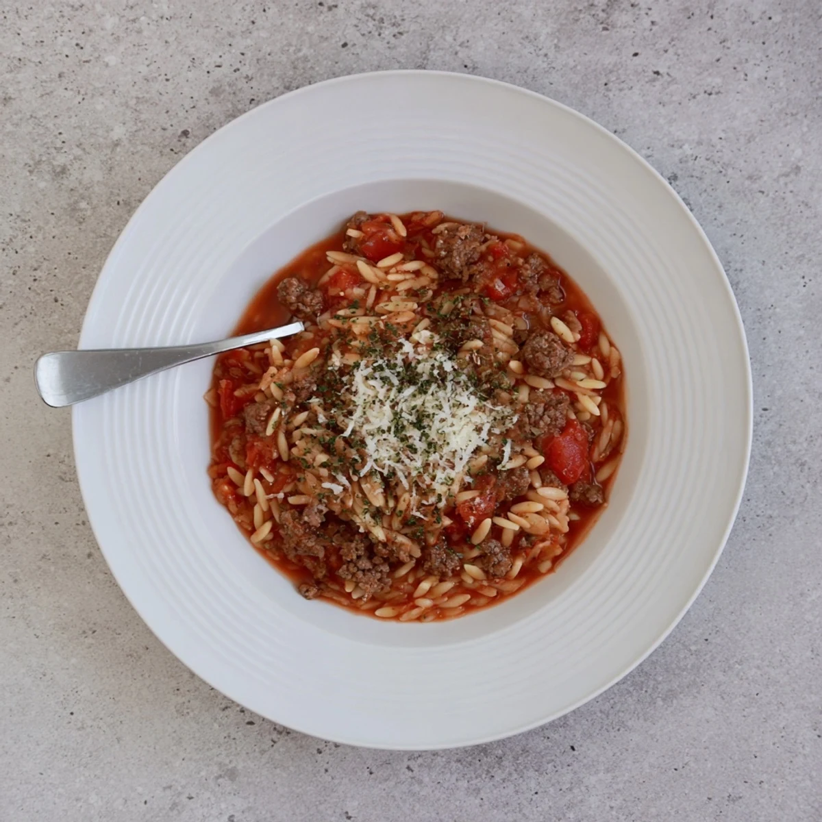 A spoonful of Ground Beef Orzo Greek Manestra Recipe reveals rich tomato aroma.