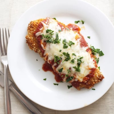 Fresh basil garnish complements the savory tomato sauce on this classic Italian-American Chicken Parmigiana dish.