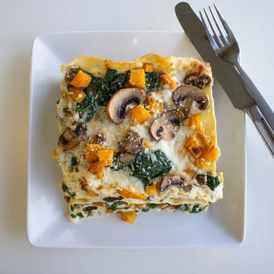 Freshly baked butternut squash lasagna served hot from the oven, topped with melted mozzarella and fresh basil garnish.